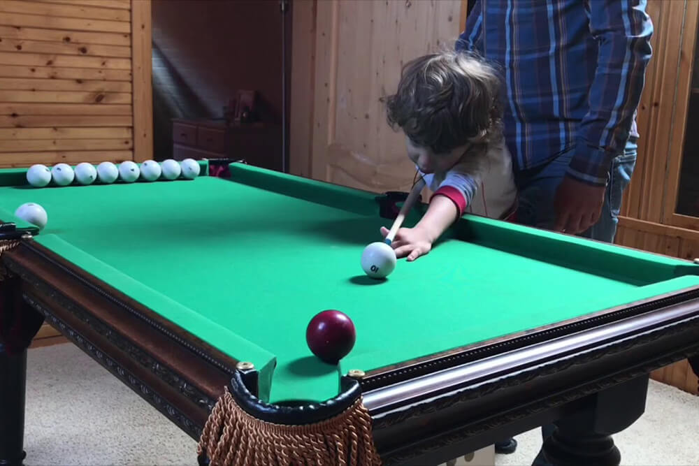 Мальчик играет в мини-бильярд